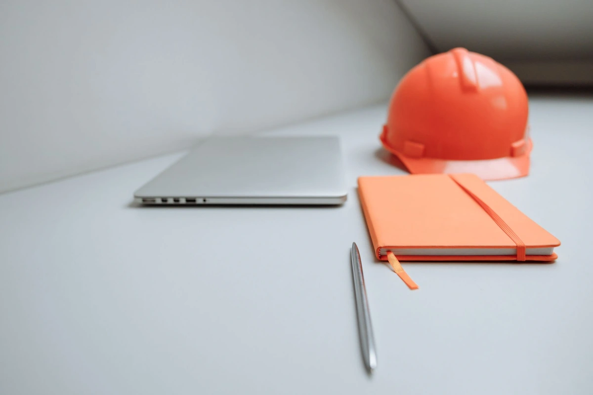 Carnet de relevé et plans posés devant une maison en travaux